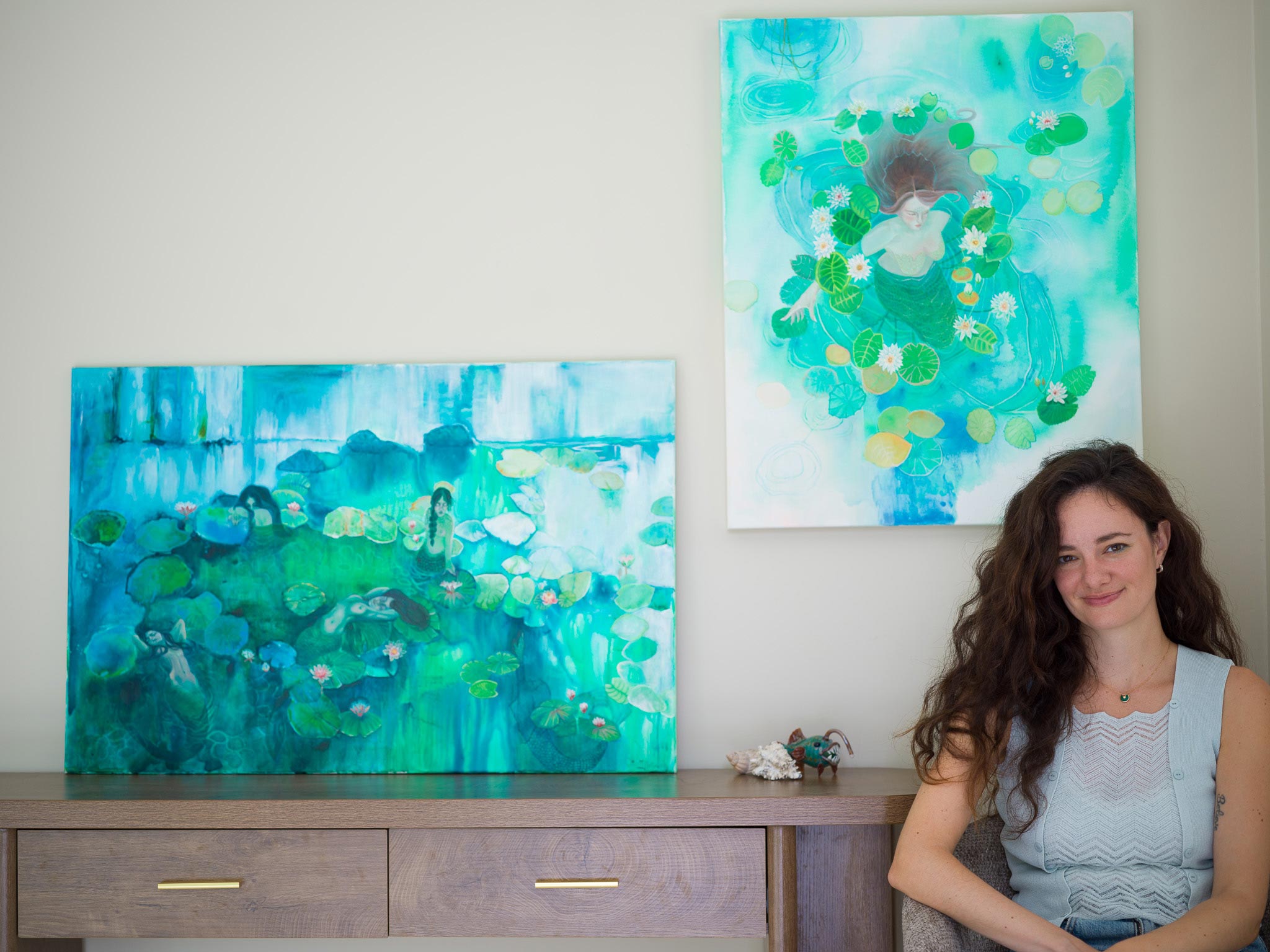 Two abstract mermaid paintings featuring green lily pads and blue water tones.